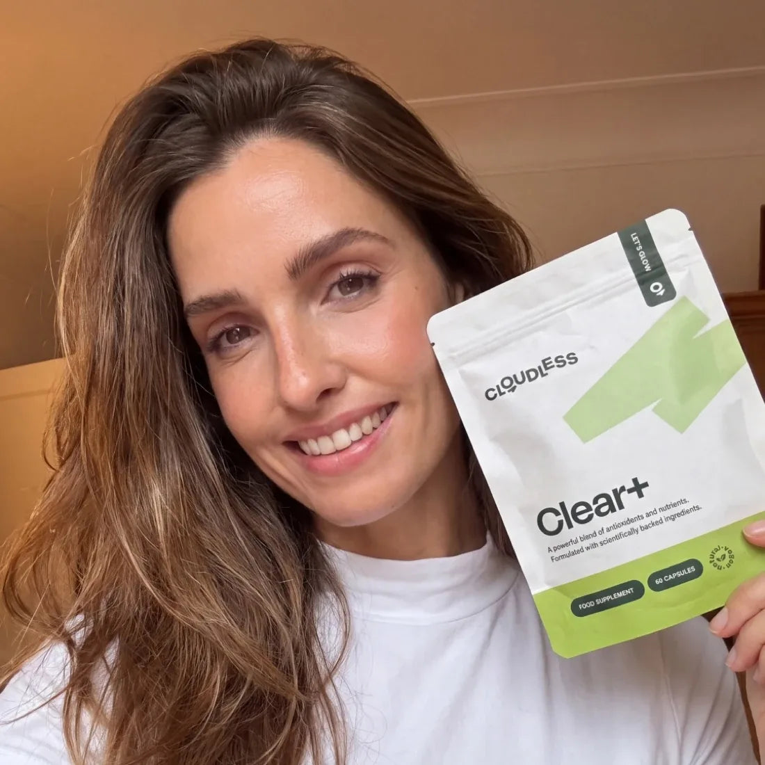 Une femme souriante à la peau plus nette tient Clear+